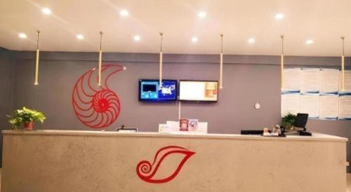 a restaurant with a reception counter with a sign of a hot dog at Shell Hotel Jiangsu Taizhou Hailing District Taizhou Avenue in Sixiang