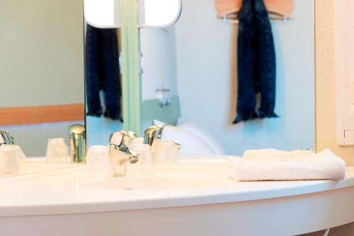 ein Bad mit einem Waschbecken und einem Spiegel in der Unterkunft ibis budget Granville in Granville