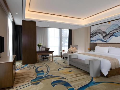 una camera d'albergo con un grande letto e una TV di Venus Royal Hotel Nanning East High-Speed Railway Station a Nanning