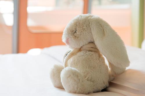 a stuffed rabbit is sitting on a bed at ibis budget Granville in Granville