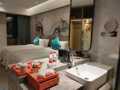 une salle de bain avec un lit, un lavabo et un miroir dans l'établissement Yinhu Junyi Hotel（Wildlife Park）, à Hangzhou