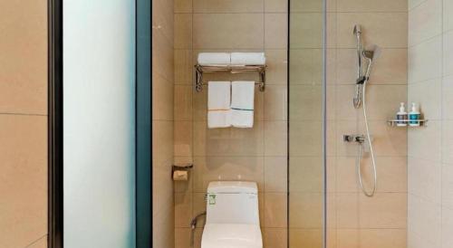 ein Badezimmer mit Toilette und Dusche mit Handtüchern in der Unterkunft City Comfort Inn Fengcheng Recycle Park Geliyang 