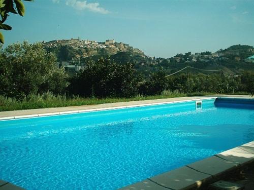 a large blue swimming pool with a city in the background at Azienda Agrituristica Biologica Il Querceto in Santa Severina