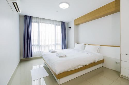 a bedroom with a large white bed with a window at Fin Banchang in Ban Nong Chaeng