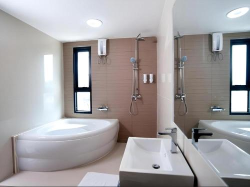 a white bathroom with a tub and a sink and a bath tub at Siamgrand Hotel in Nakhon Phanom