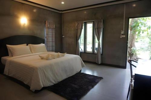 une chambre avec un grand lit blanc avec une fenêtre dans l'établissement V Valley Resort, à Satun