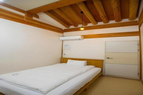 a small bedroom with a white bed and a closet at Nabijam Hanok Hotel in Jeonju