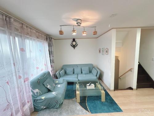 a living room with a blue couch and a glass table at 新規OPEN8割！1棟貸切・10名可能！秋葉原まで13分、新宿まで32分／スカイツリー近く in Tokyo