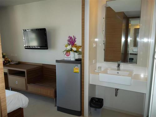 a bathroom with a sink and a mirror and a tv at Honey Lodge in Pattaya South