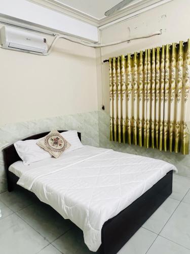 a bedroom with a white bed with gold accents at An Long Hotel in Ấp Ðông An (1)