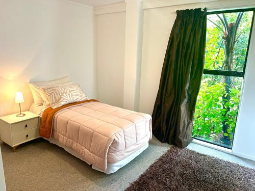 a bedroom with a bed and a large window at St Okes Apartment- Peaceful retreat set in native bush Stay 1 night, 1 week or 1 month in Lower Hutt
