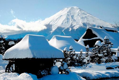 a snow covered mountain in the distance with a house at Guesthouse E-ne in Oshino