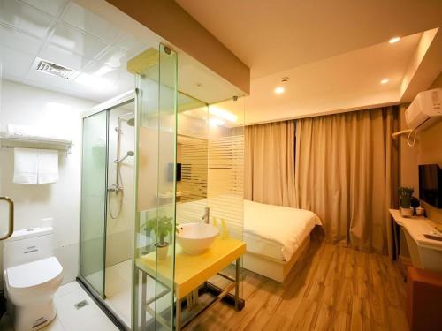 a bathroom with a sink and a toilet and a bed at Shell Jiaxing Nanhu District Dongsheng Dong Road Moon River Street Hotel in Jiaxing