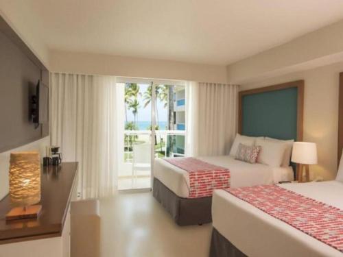 a hotel room with two beds and a balcony at Celuisma Playa Dorada All Inclusive in San Felipe de Puerto Plata