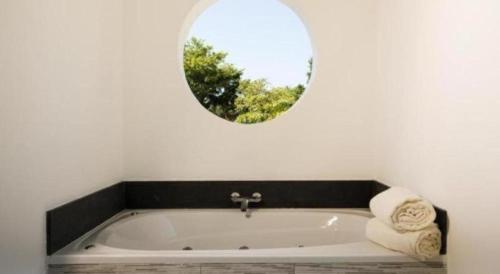 a bathroom with a bath tub with a round mirror at Celuisma Playa Dorada All Inclusive in San Felipe de Puerto Plata