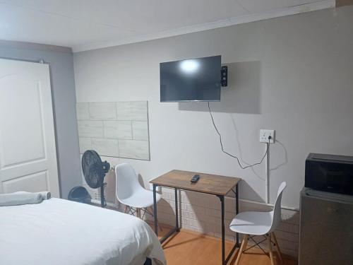 a bedroom with a bed and a table and a tv at Blackwood Guest house in Vereeniging
