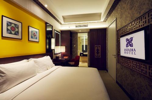 a hotel room with a bed and a yellow wall at Estadia Hotel in Melaka