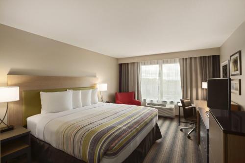 una habitación de hotel con una cama grande y una silla roja en Country Inn & Suites by Radisson, San Antonio Medical Center, TX, en San Antonio