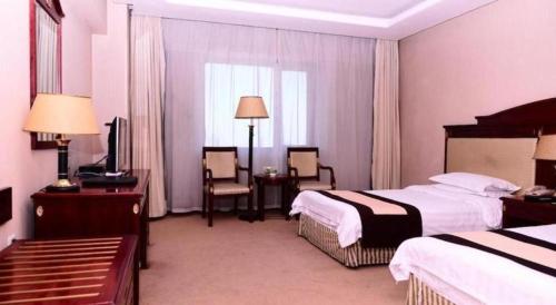 a hotel room with two beds and a television at Heilongjiang Kunlun Hotel in Harbin