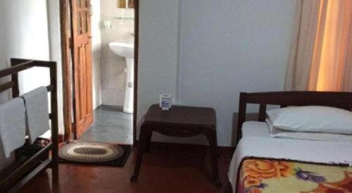 ヌワラエリヤにあるSt. Andrews Hostelのベッドとテーブルと洗面台のある寝室