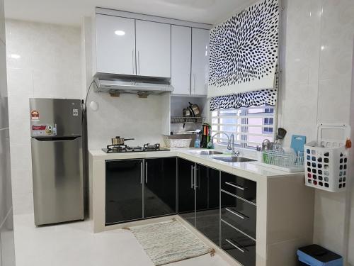 uma cozinha com armários brancos e um frigorífico de aço inoxidável em Ummi Guesthouse em Dungun