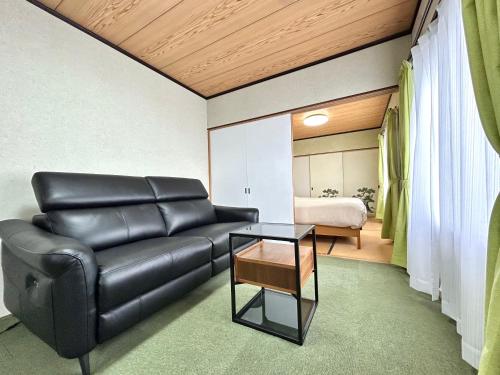 a living room with a black leather couch and a table at Powder Snow 粉雪 in Furano