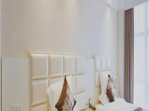 a bedroom with a white headboard with pillows on a bed at Changshu Please Hotel in Changshu