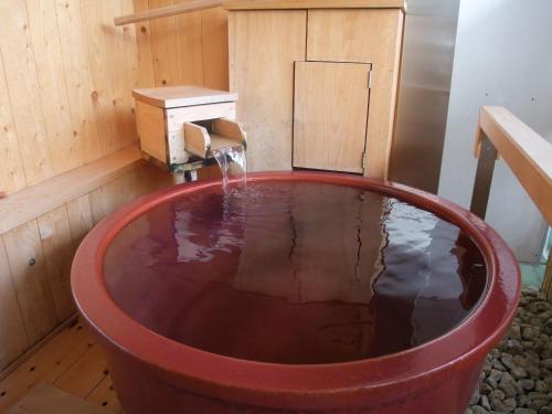 a bath tub filled with water in a wooden room at Asanoya in Shinonsen