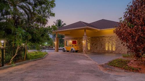 a house with a yellow car parked in a driveway at The Ranch Kakkadampoyil - a VKation Experience in Kakkadampoyil