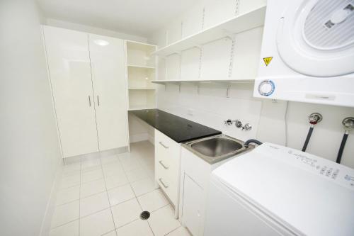 a white kitchen with white cabinets and a sink at Gladstone City Central Apartment Hotel Official in Gladstone
