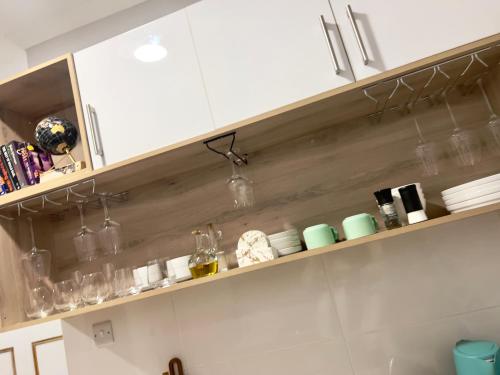 eine Küche mit weißen Schränken und Gläsern auf dem Regal in der Unterkunft Sarona LoLa E206 in Gaborone