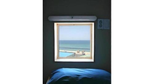 a window in a bedroom with a view of the ocean at Capsule Inn Gangneung in Gangneung