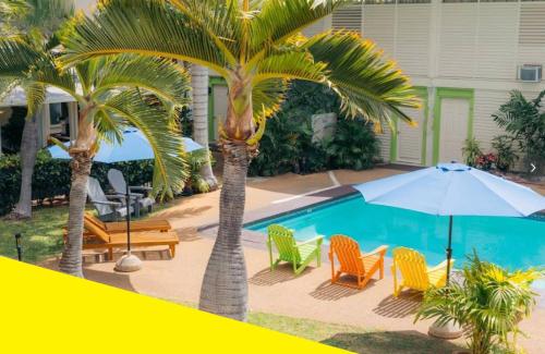 a pool with chairs and an umbrella and palm trees at Bposhtels Waikiki Retreat in Honolulu
