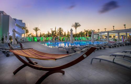 a hammock in a resort with chairs and a pool at Nicholas Color Hotel in Ayia Napa