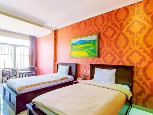 two beds in a room with orange walls at Albis Hotel in Bandung