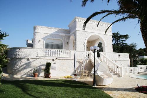a white house with a porch and a lawn at Villa Angelina in Selva di Fasano