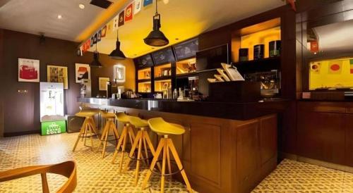 a bar with yellow stools in a restaurant at Tematik Hotel Pluit in Jakarta