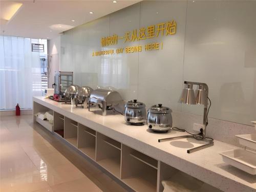 a kitchen with several pots and pans on a counter at City Comfort Inn Dangtu High Speed East Railway Station RT-Mart in Ma'anshan