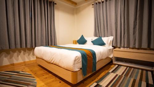 Un dormitorio con una cama grande con almohadas azules. en Hotel Oms Home, en Tukucha
