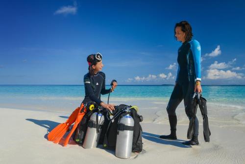 two people in wetsuits standing on the beach at Adaaran Select Meedhupparu - with Dine around Premium All inclusive - 24 hours in Meedhoo