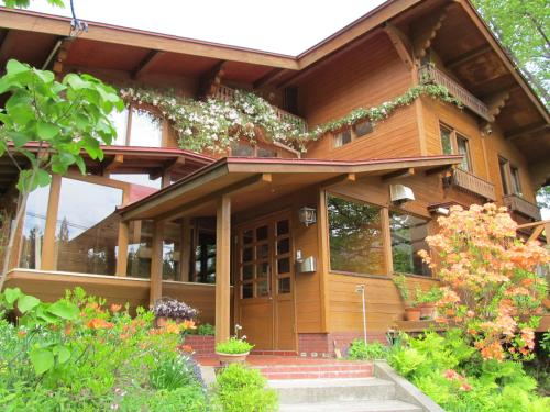 a wooden house with a door and some flowers at ペンション木いちご PensionKiichigo in Zaō Onsen