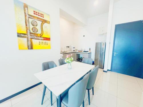 a dining room with a white table and blue chairs at Opus Residences by Ardent Homes in Kuala Lumpur