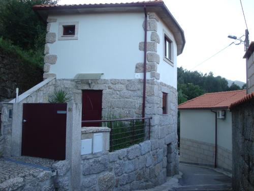 a white house with a door in a stone wall at Casa da Ficheira in Geres