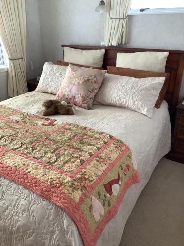 a dog laying on top of a bed with a blanket at Puti Puti BNB in Kaitaia