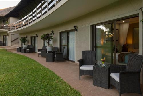 a patio with chairs and tables on a building at Azambezi River Lodge in Victoria Falls
