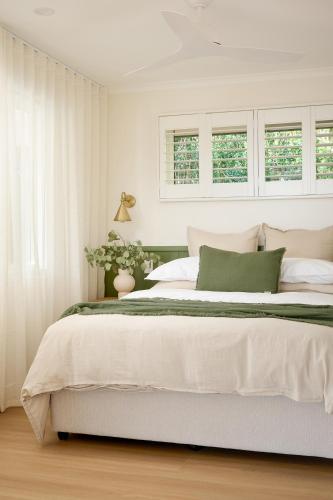 a bedroom with a large bed with white walls and windows at Oak Ridge Cottage in Maleny