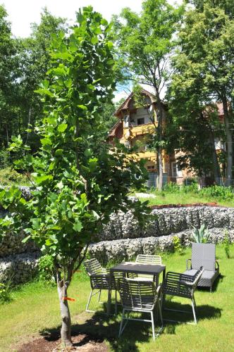 a table and chairs next to a table and a tree at Boutique Hotel Sudetia - Medical & SPA in Świeradów-Zdrój
