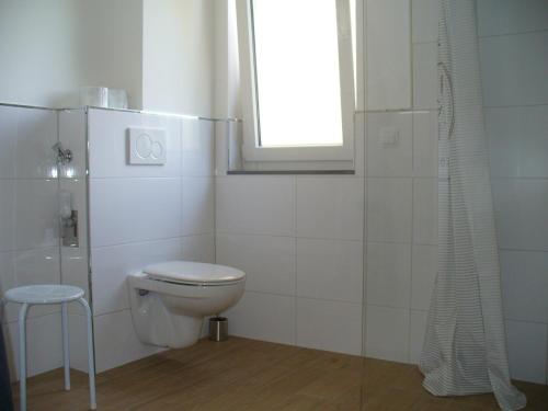 ein weißes Bad mit einem WC und einem Fenster in der Unterkunft Ferienwohnung Rheinaue in Köln