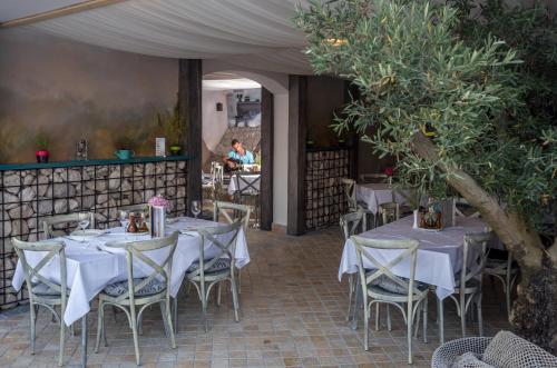 a restaurant with white tables and chairs and a tree at Hotel Perla in Herceg-Novi