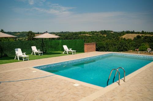a swimming pool with two chairs and a table at Vila Mitrović in Ljig